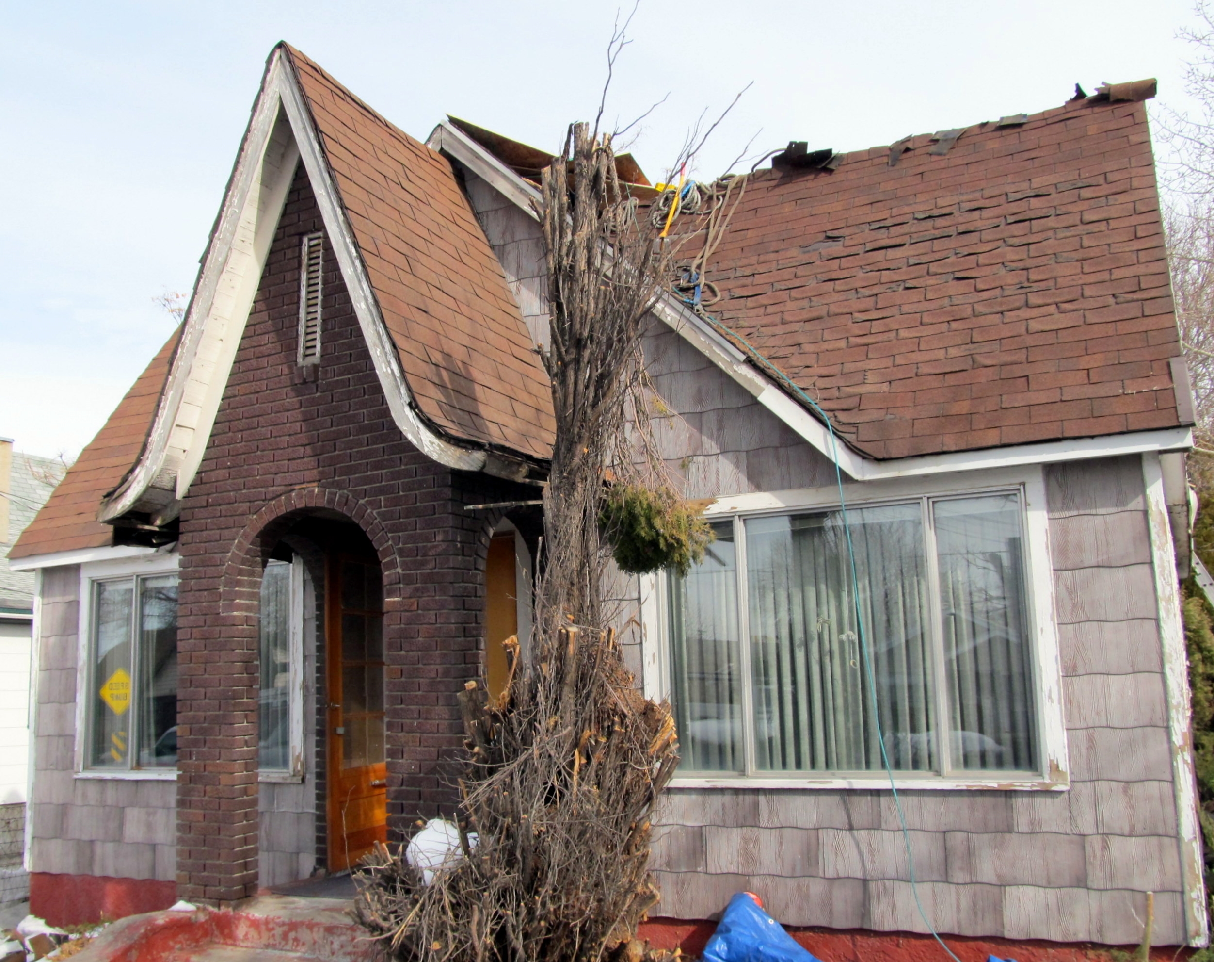 Before photo of tudor home with shingles flaking off of the roof